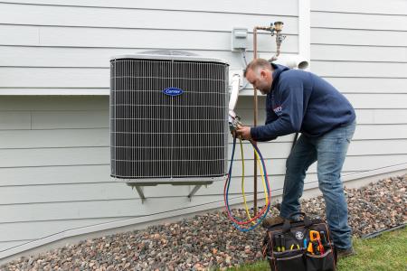 Lofgren Heating & Air Conditioning Repairman working on a Carrier Air Conditioner.